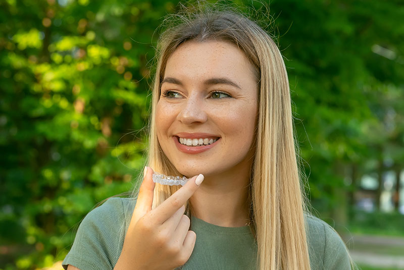 lady with green shirt holding clear aligner